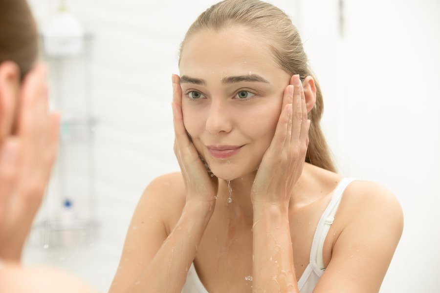 Woman washing her face with water Woman washing her face with water