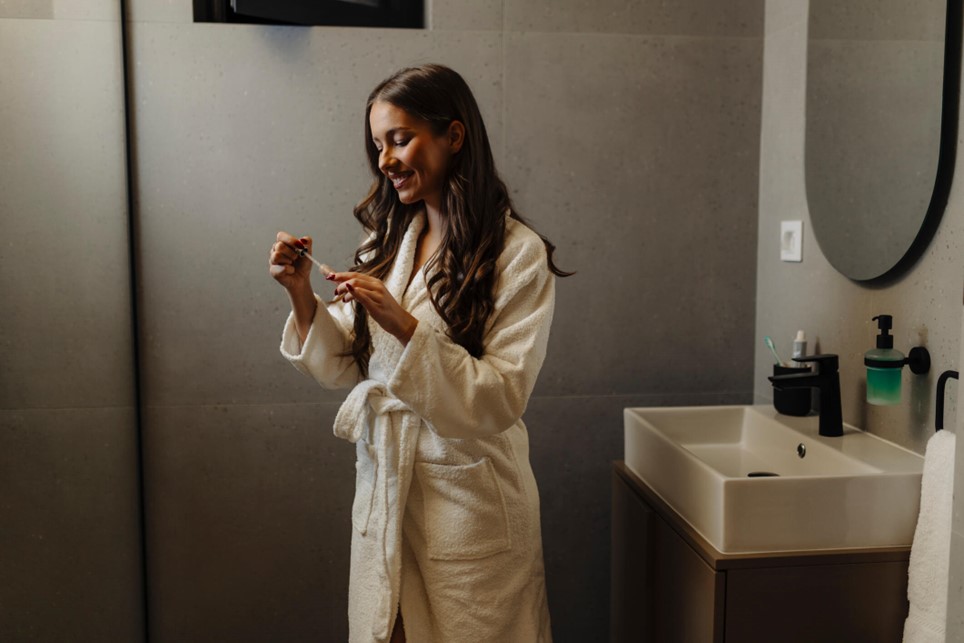 A person in a bathrobe using skincare product