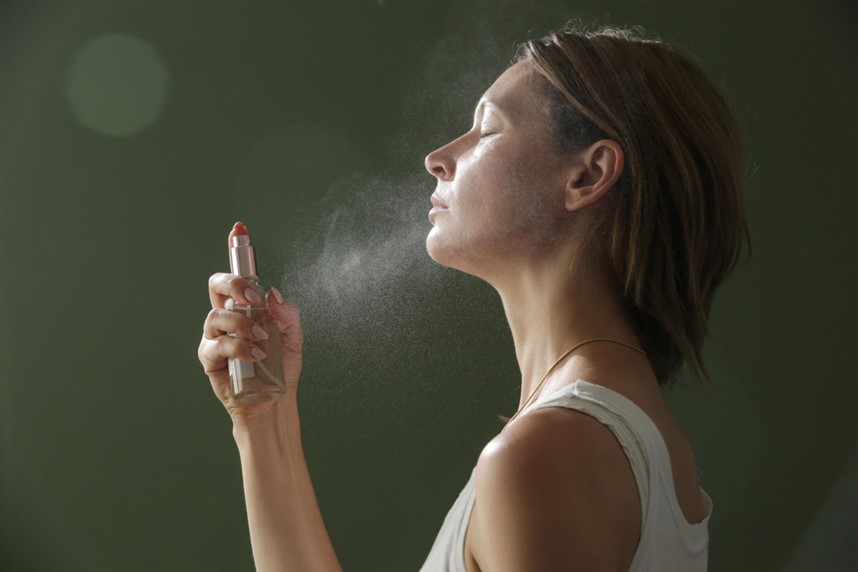 A person spraying a skincare product on their face