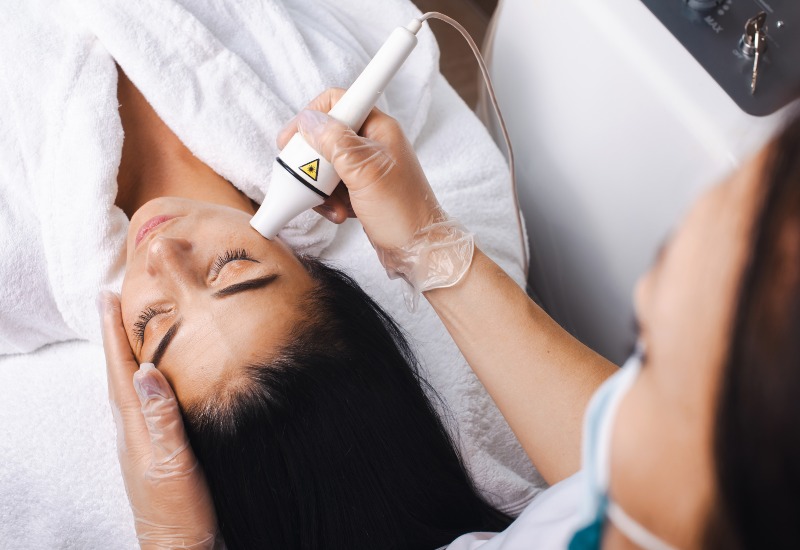 An expert is offering laser therapy treatment on a patient's face in Dallas & the nearby area