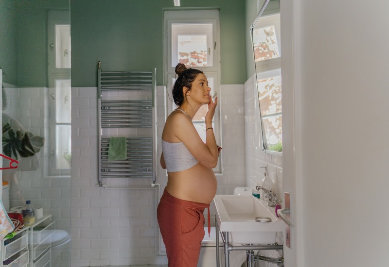 A pregnant woman is providing herself a skincare in Dallas, TX, and surrounding area